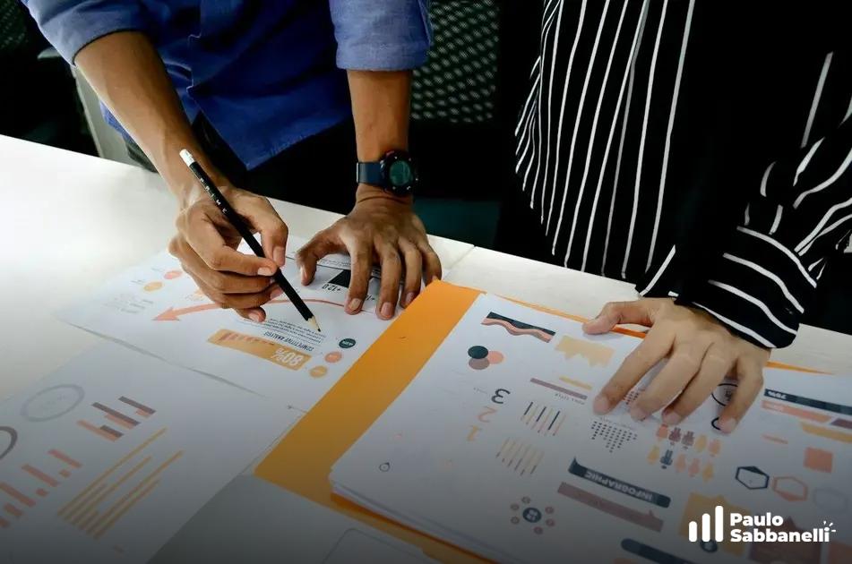 Duas pessoas apontam para relatório impresso com gráficos e infográficos coloridos