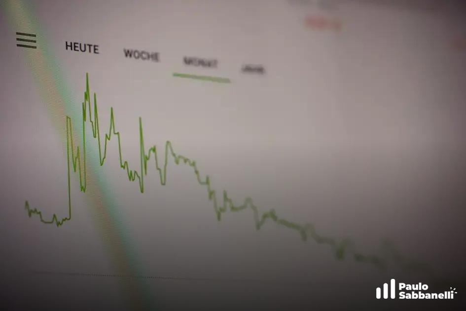 Gráfico de linha verde em tela desfocada mostra queda de valores ao longo do tempo, com filtros de período
