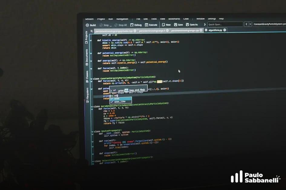 Monitor fotografado à distância em sala escura com código Python aberto na aba algorithm.py