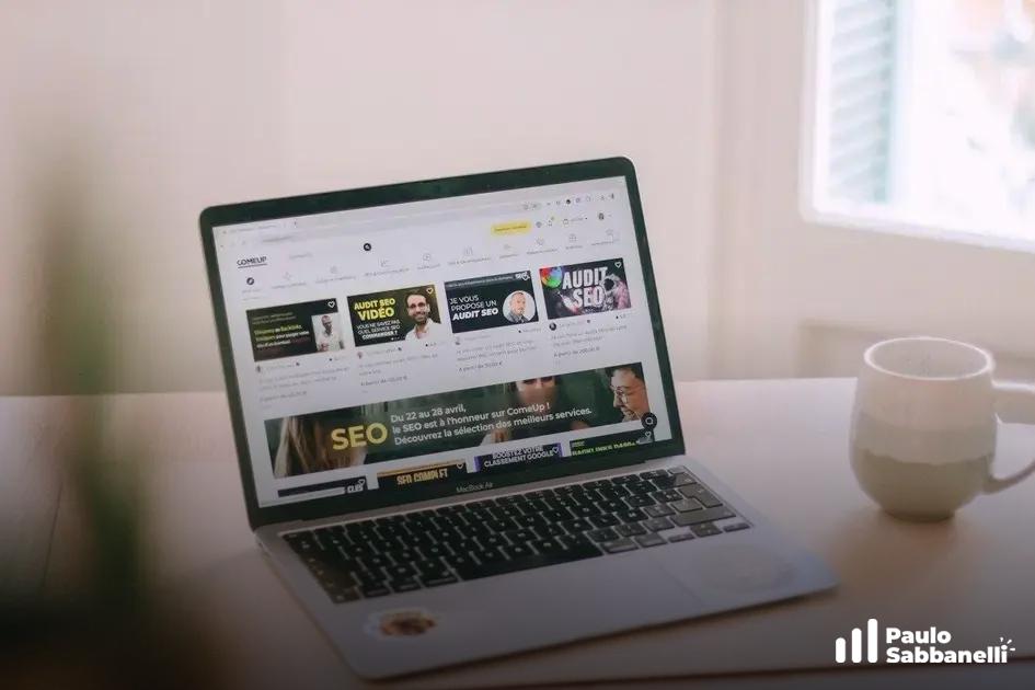 Notebook sobre mesa exibe site com conteúdo sobre auditoria de SEO, xícara de café ao lado