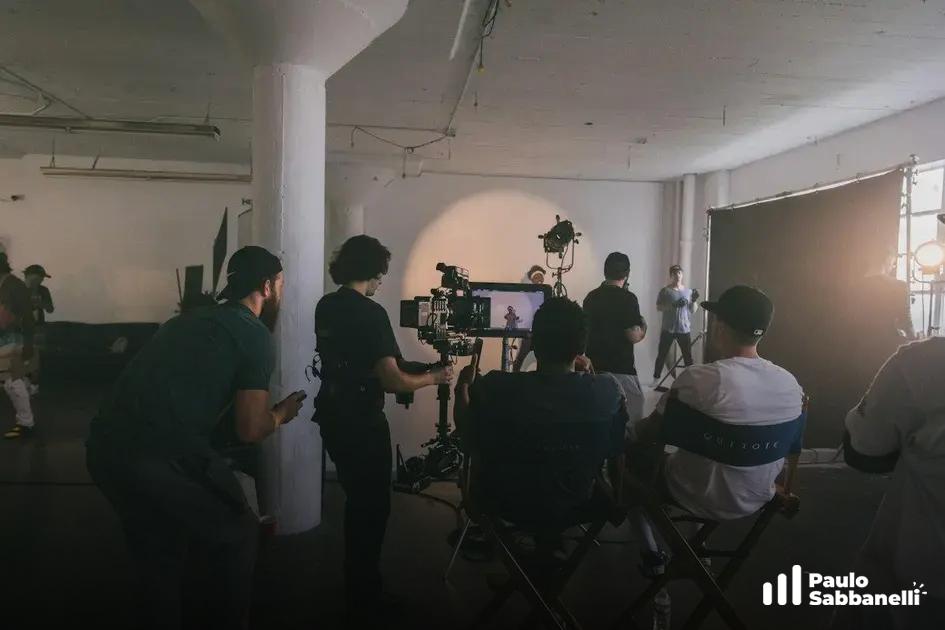Equipe de produção grava vídeo em estúdio industrial com câmera em tripé e luz de apoio