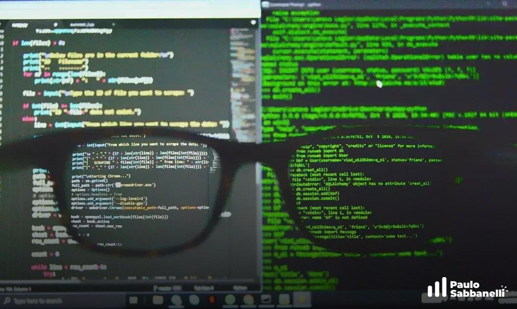 Óculos em primeiro plano com dois monitores ao fundo exibindo código em terminal verde